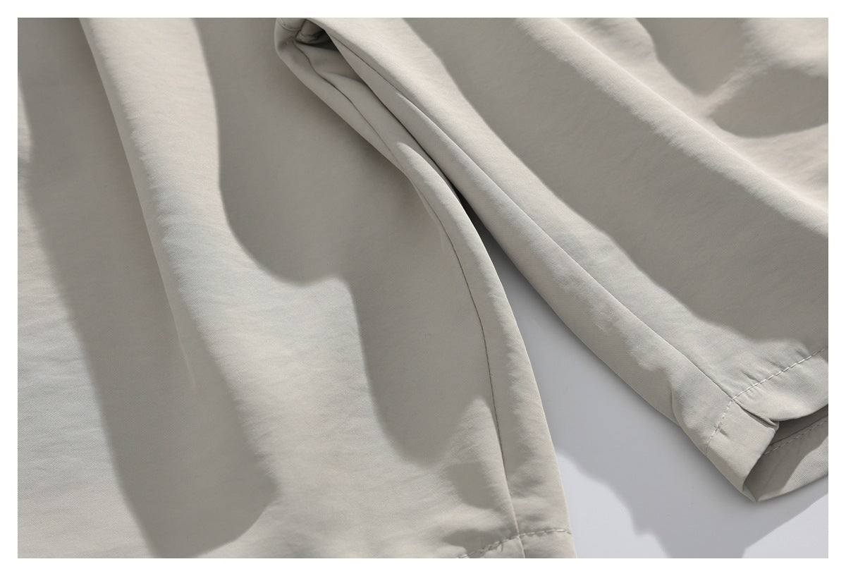 Close-up of a folded trouser leg and stitched hem on light beige trousers.