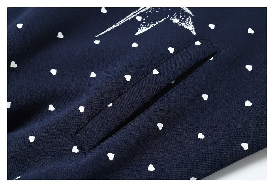 Close-up of a slanted welt pocket on a navy hoodie patterned with small white hearts.