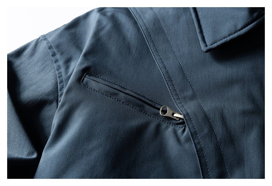 Close-up of a dark navy jacket showing a slanted zip pocket and stitched front placket.