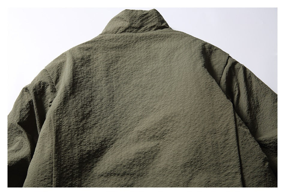 Back view of an olive textured jacket laid flat, with a raised collar and long sleeves.