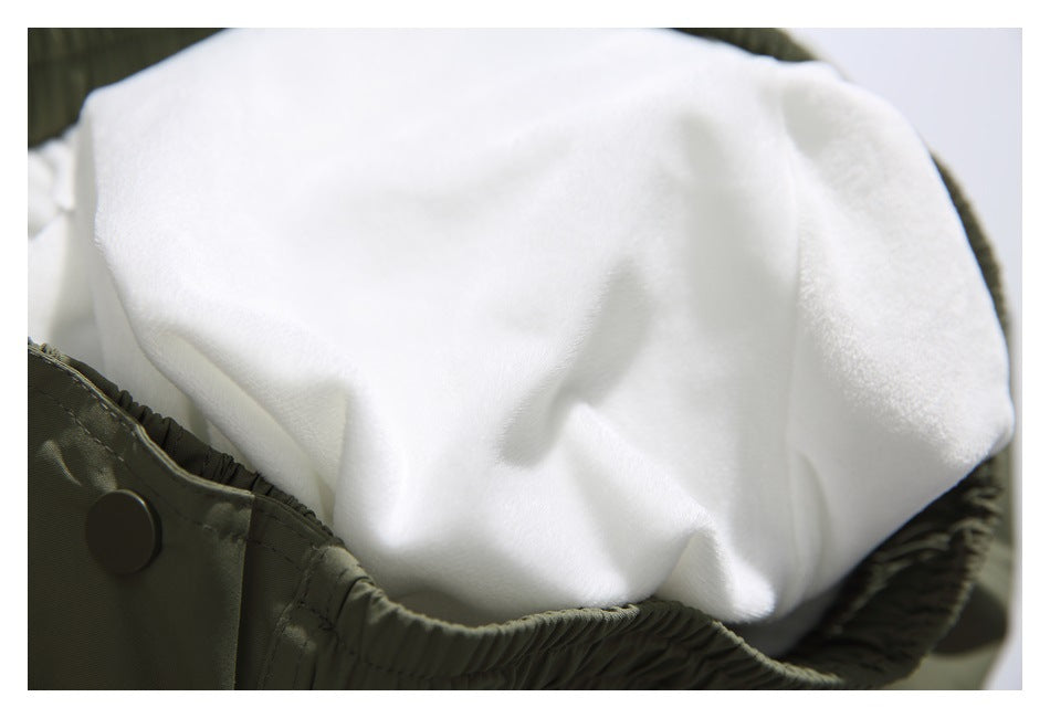 Close-up of soft white lining inside olive-green pants, beside the gathered edge and a snap button.