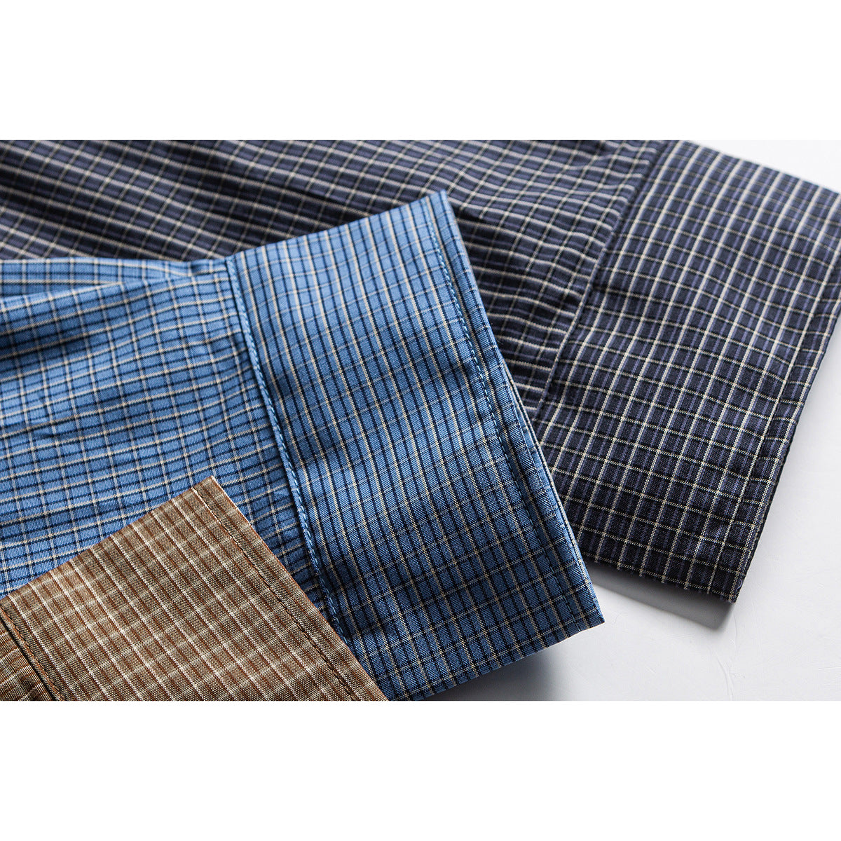 Several overlapping plaid shirt sections in blue, brown, and dark charcoal colorways.