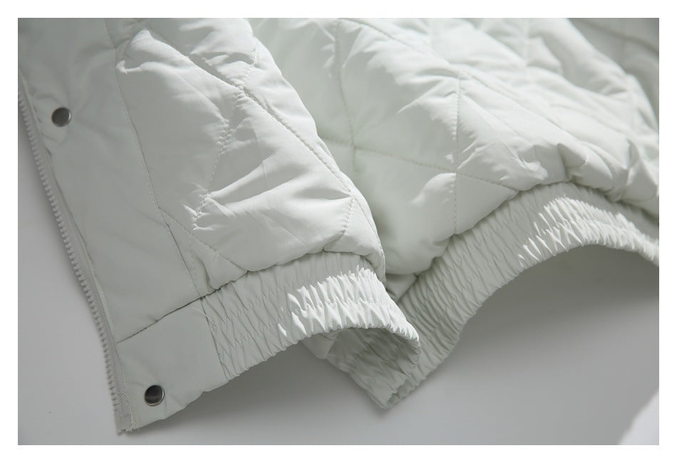 Close-up of the white jacket's quilted lower edge and gathered elastic hem.