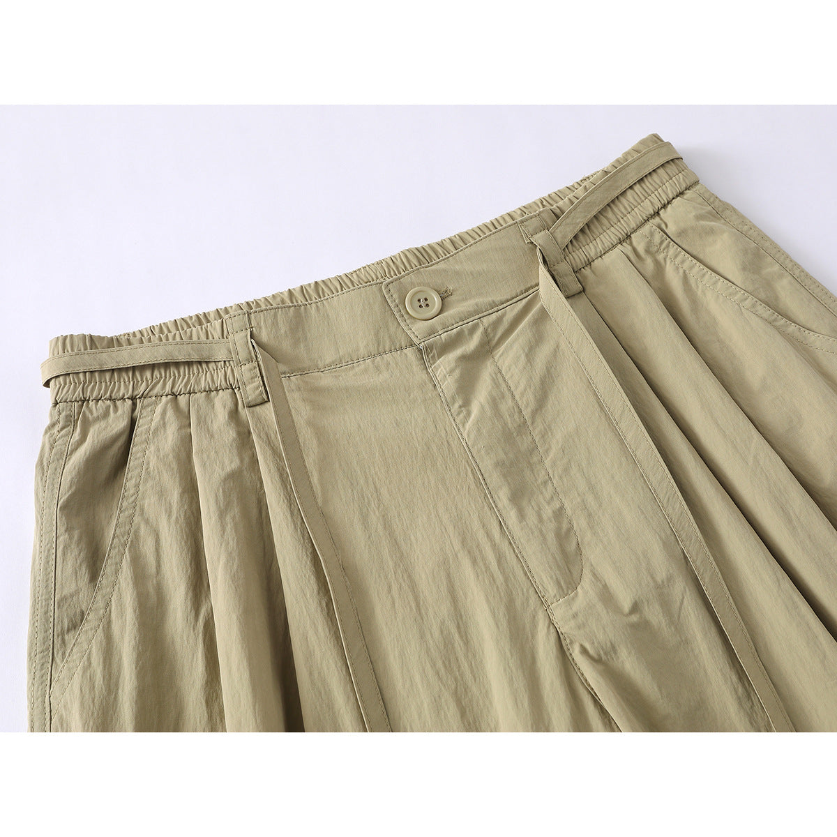 Close-up of khaki shorts showing the elastic waistband, button closure, belt loops, and pleated front.