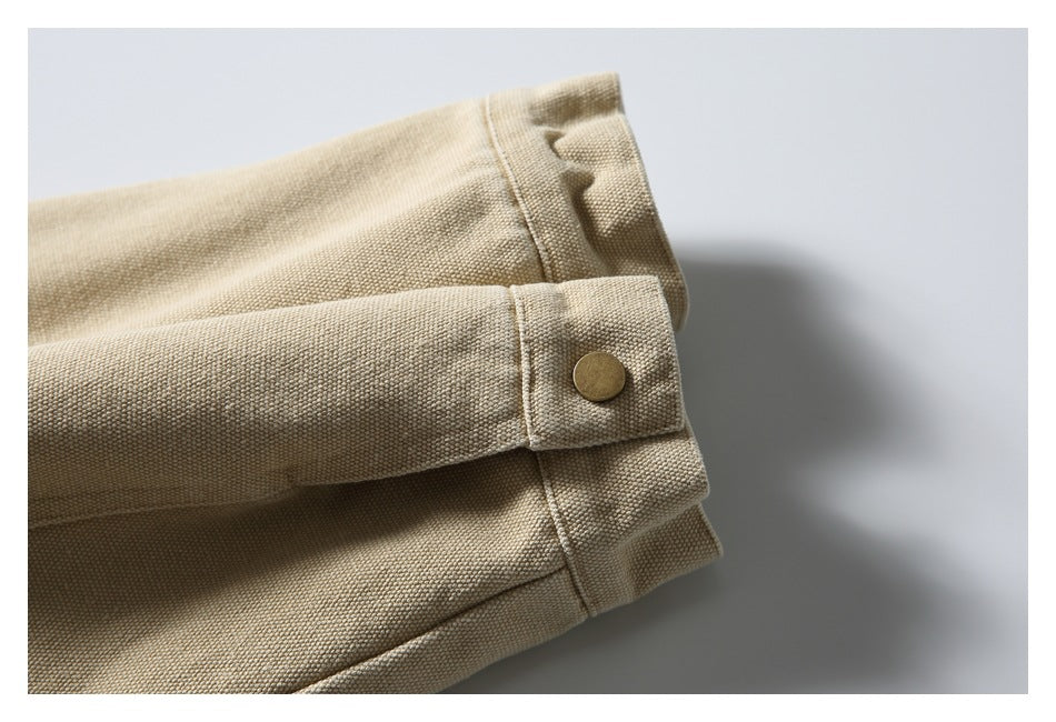 Close-up of the beige jacket’s sleeve cuff with a bronze snap button.