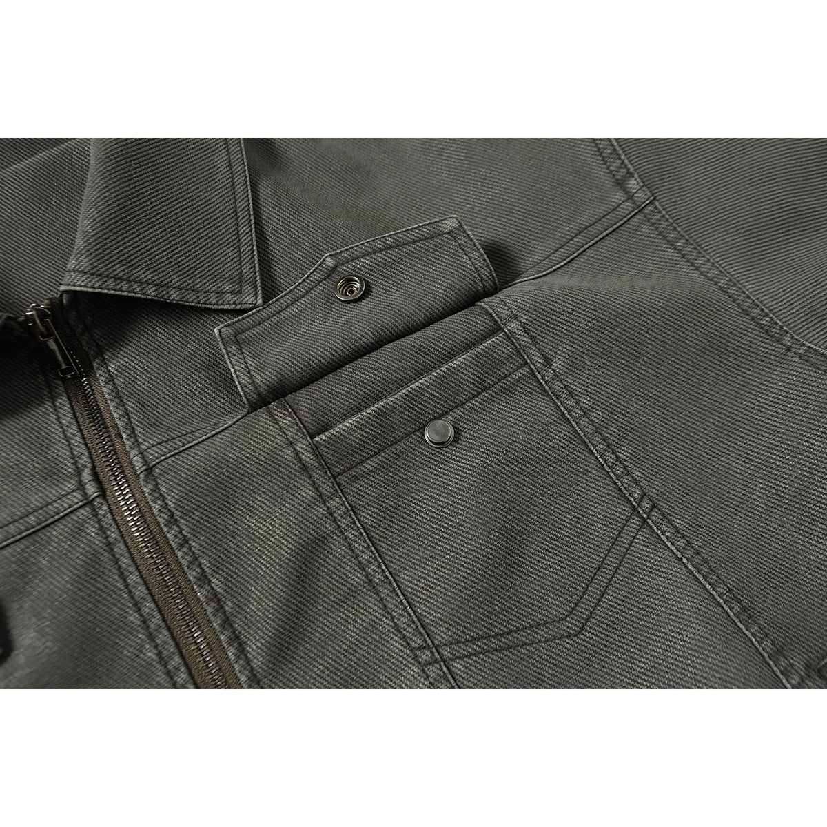 Close-up of the charcoal gray jacket's snap-fastened chest pocket and front zipper.