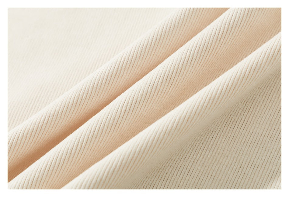 Close-up of pale ivory ribbed garment fabric arranged in soft folds.