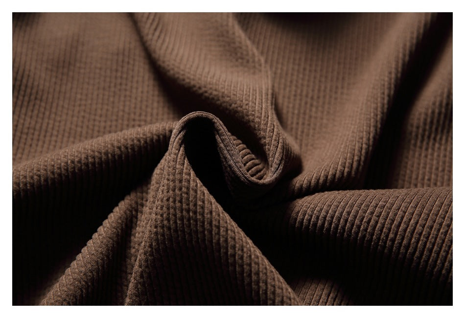 Close-up showing the brown sweatshirt's raised ribbed knit texture and folded fabric.