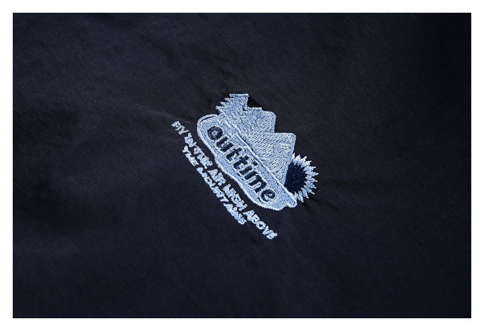 Close-up of a light-colored embroidered emblem on black garment fabric.