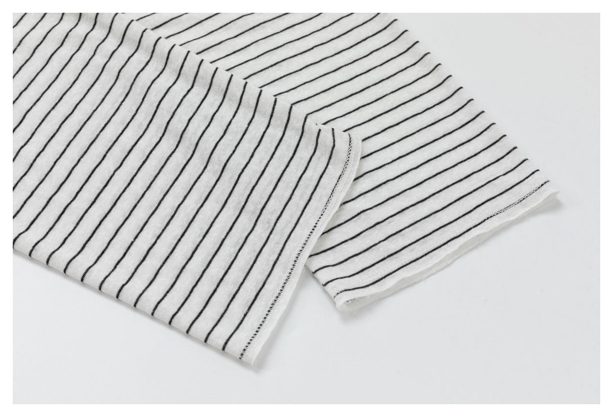 Close-up of a white garment with thin black stripes and a stitched edge.