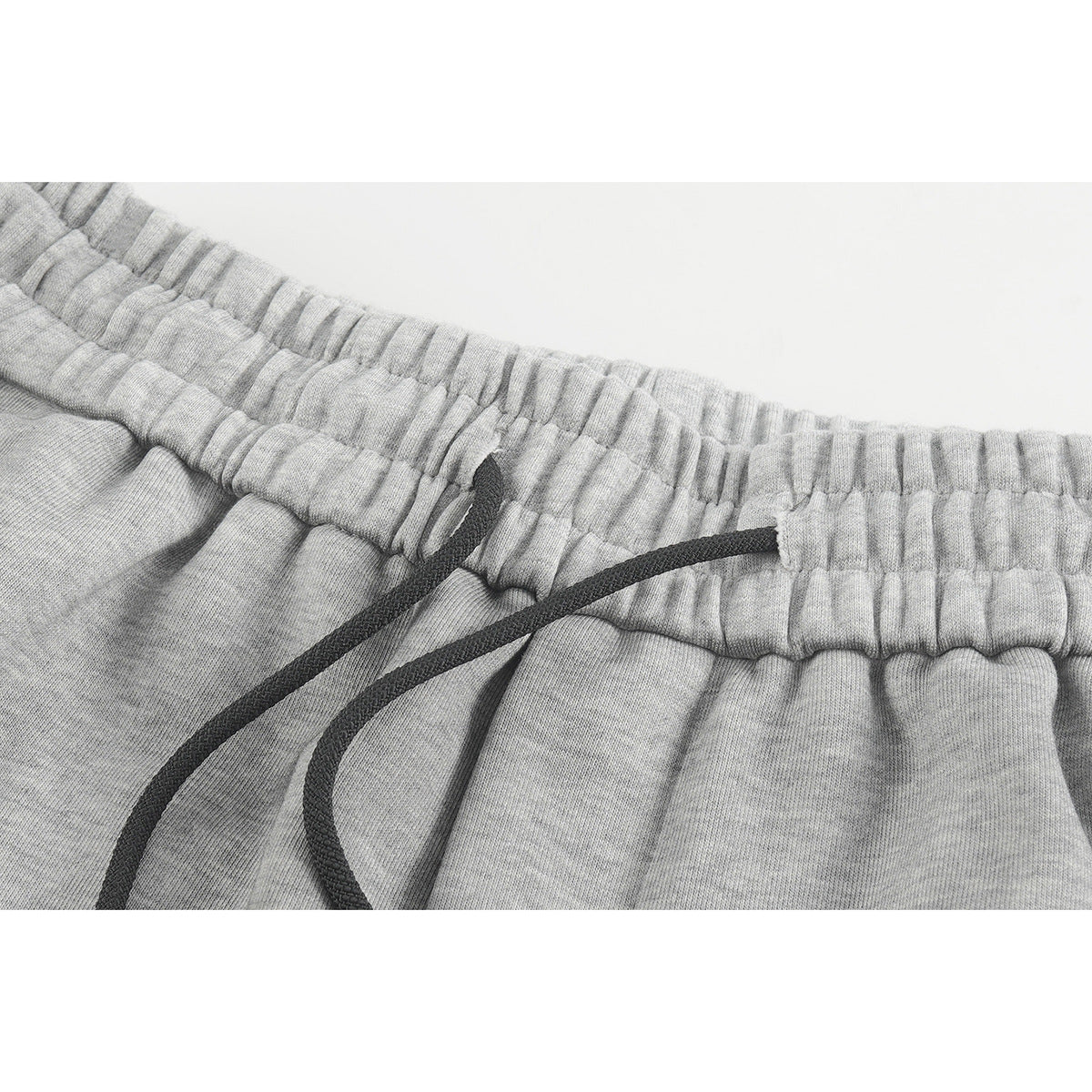 Close-up of light gray shorts showing the gathered waistband and black drawstring.