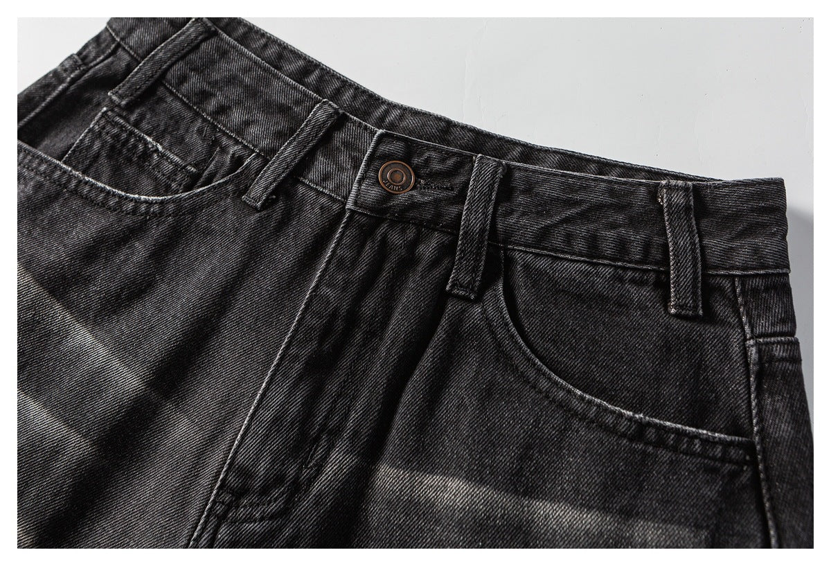 Close-up of the front waistband, button, belt loops, and pockets on black washed denim shorts.
