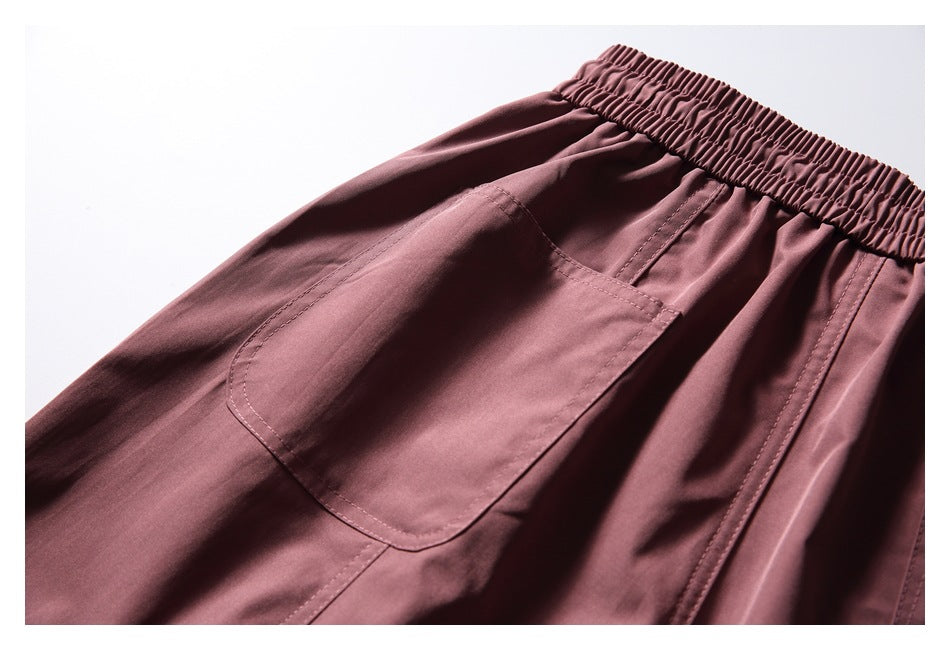 Close-up of a large patch pocket and elastic waistband on dusty mauve trousers.
