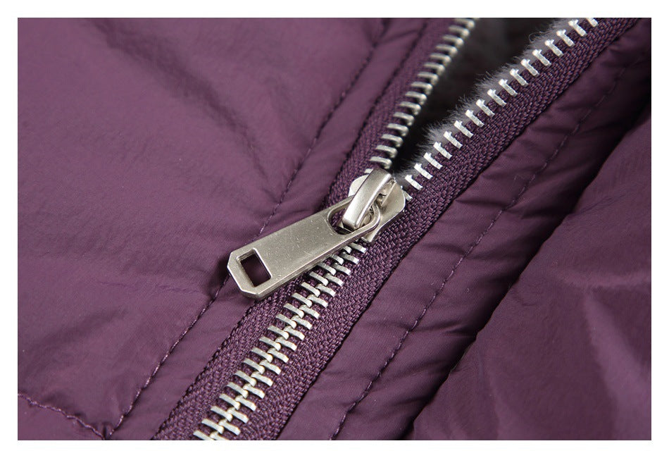 Close-up of a silver zipper and pull on plum-purple quilted fabric.