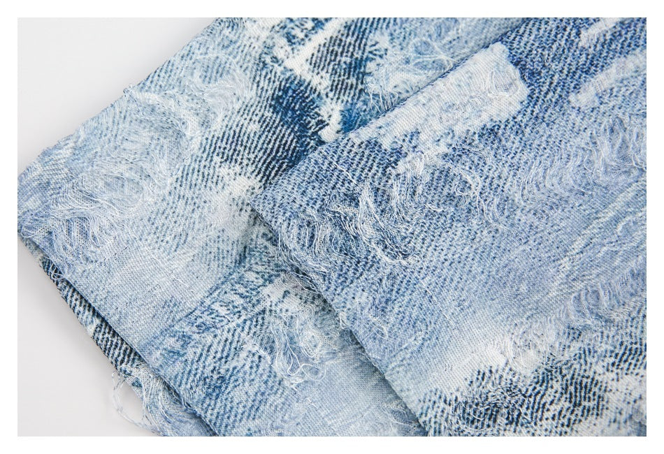 Close-up of pale blue patterned fabric with dense frayed, distressed patches and loose threads.