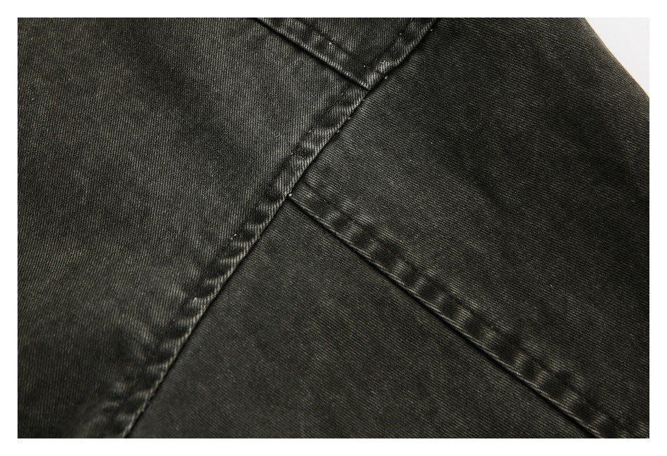 Close-up of intersecting stitched seams on dark charcoal garment fabric.