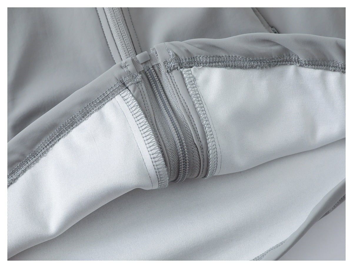 Inside view of a light gray garment showing overlock stitching and zipper construction.