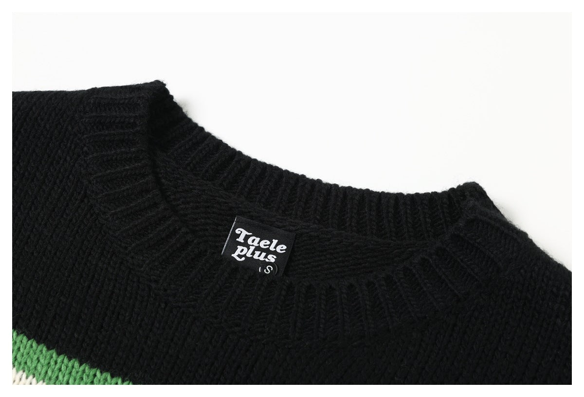 Close-up of a black sweater neckline with a sewn Taele Plus label and a glimpse of green and cream stripes.