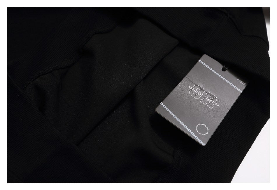 Close-up of the black sweatshirt with a dark rectangular branded hangtag.