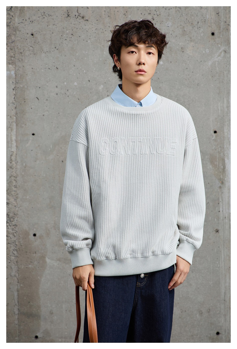 Model wearing an off-white textured crewneck sweater over a pale blue collared shirt.