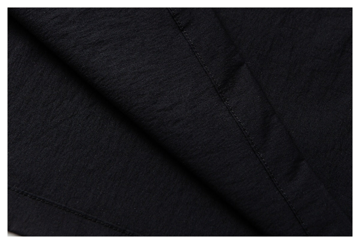Close-up of black garment panels with diagonal folds and visible stitched seams.