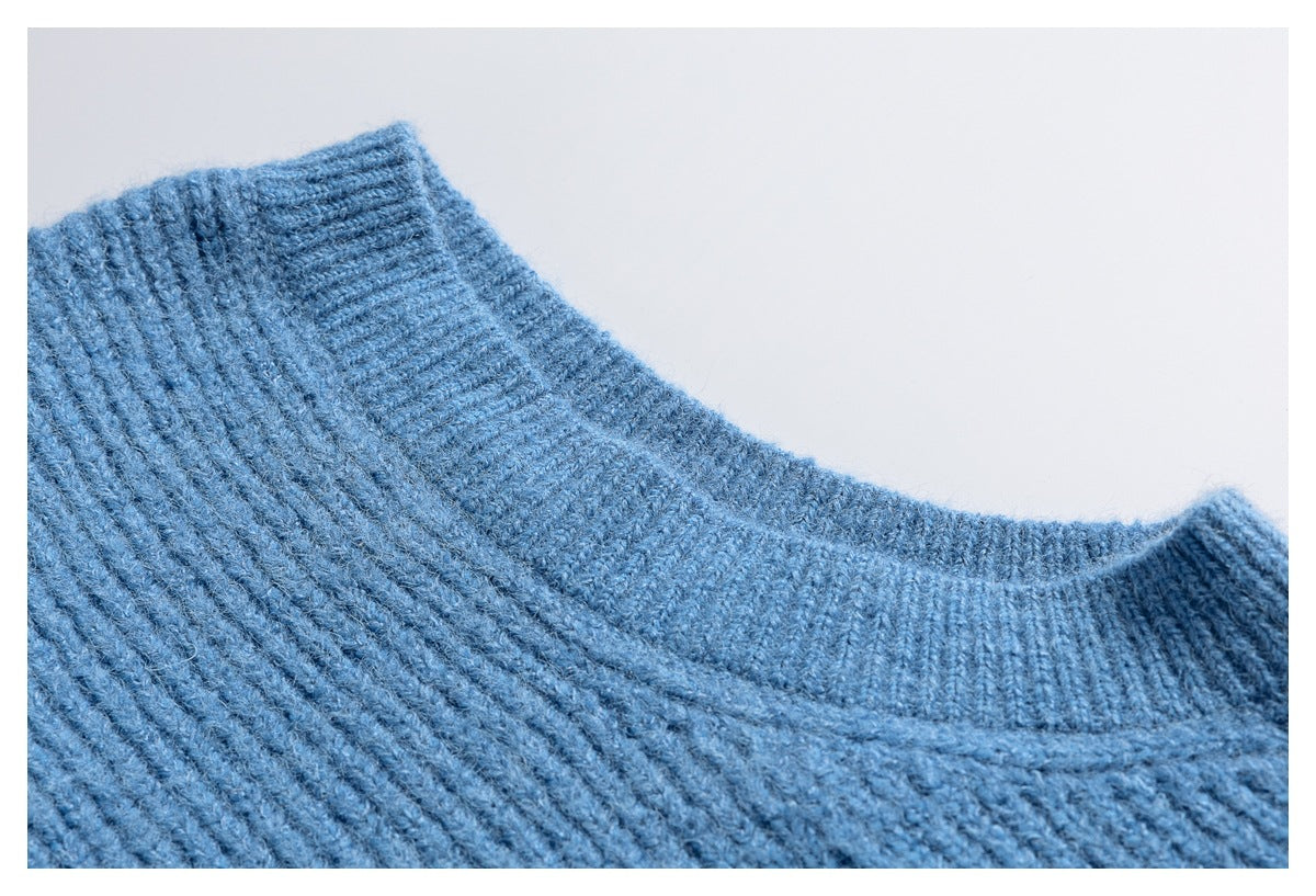 Close-up of a blue knitted sweater’s ribbed crew neckline and shoulder seam.