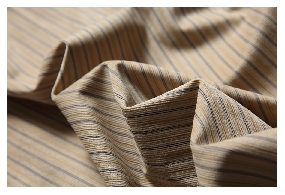 Draped close-up showing the fine brown and gray stripes and texture of beige shirt fabric.