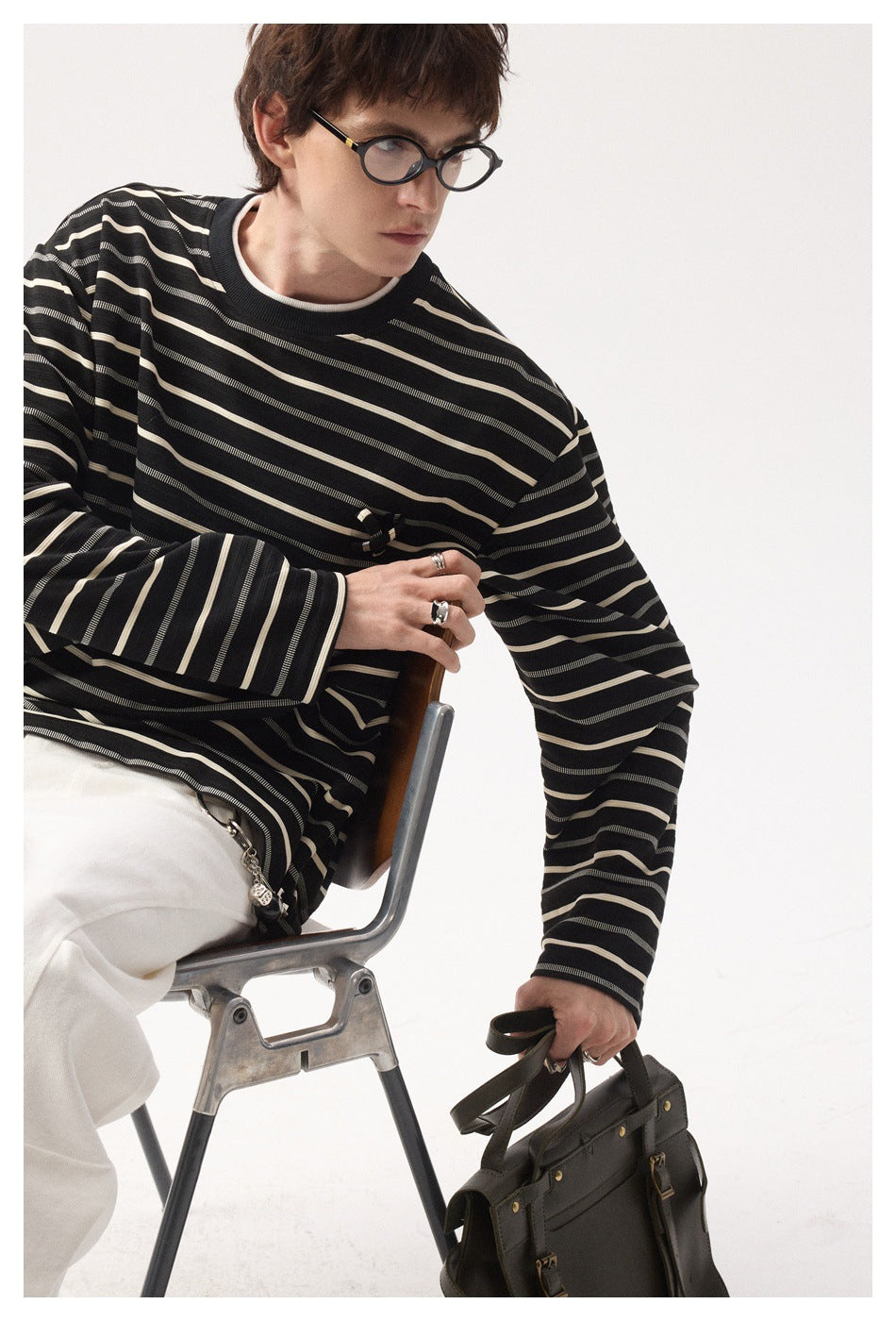 Seated model wearing a black long-sleeve shirt with cream and gray stripes and a small chest embellishment.