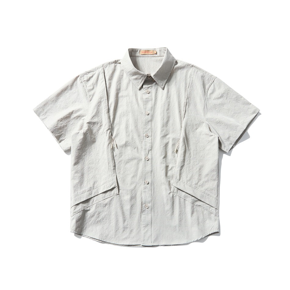 Beige-gray short-sleeve button-up shirt, flat lay front view with textured fabric and angled side panels