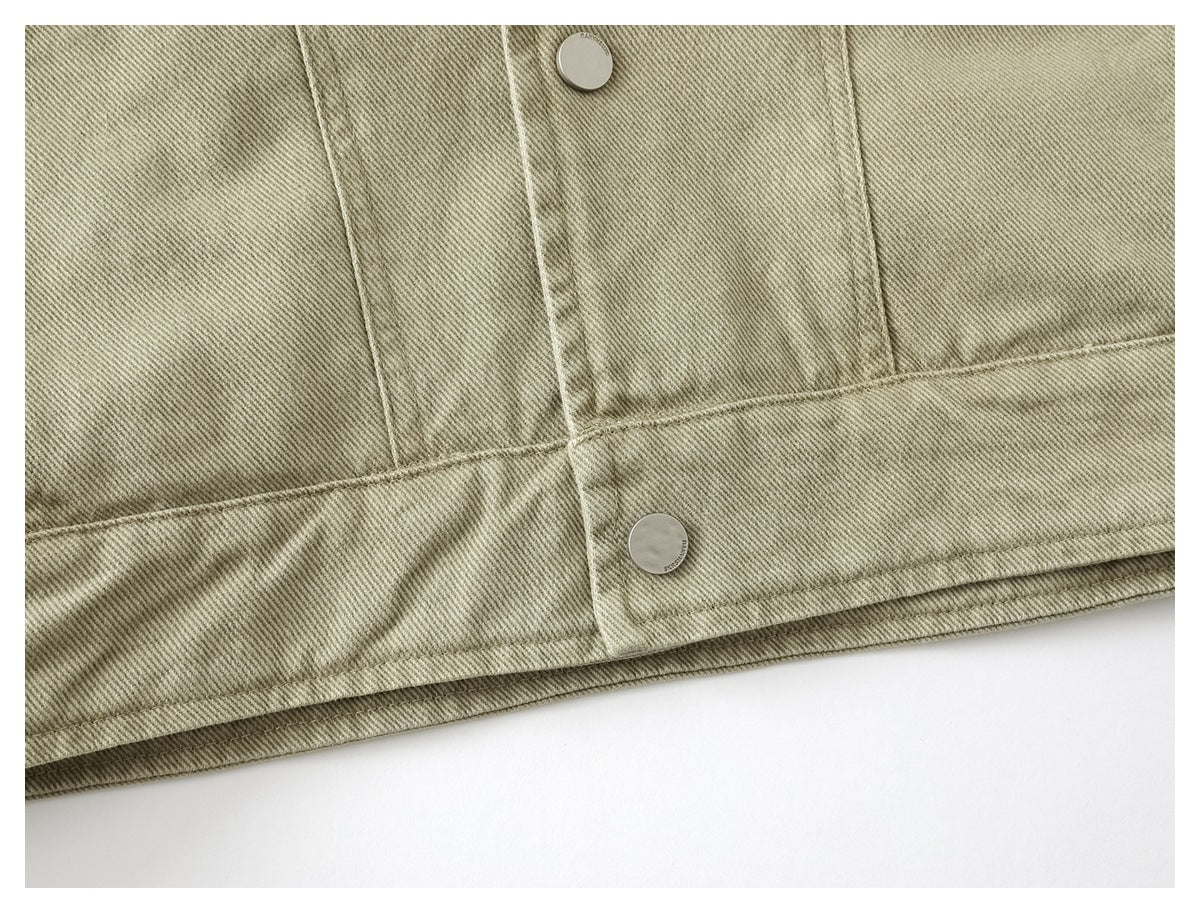 Close-up of the jacket's lower back hem with a snap-button adjustment tab in muted khaki twill.
