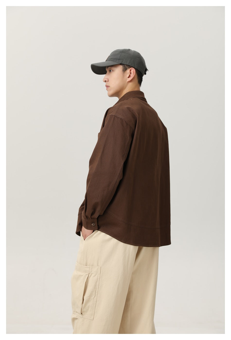 Framed back three-quarter view of a model wearing a dark brown shirt jacket and cream cargo pants.