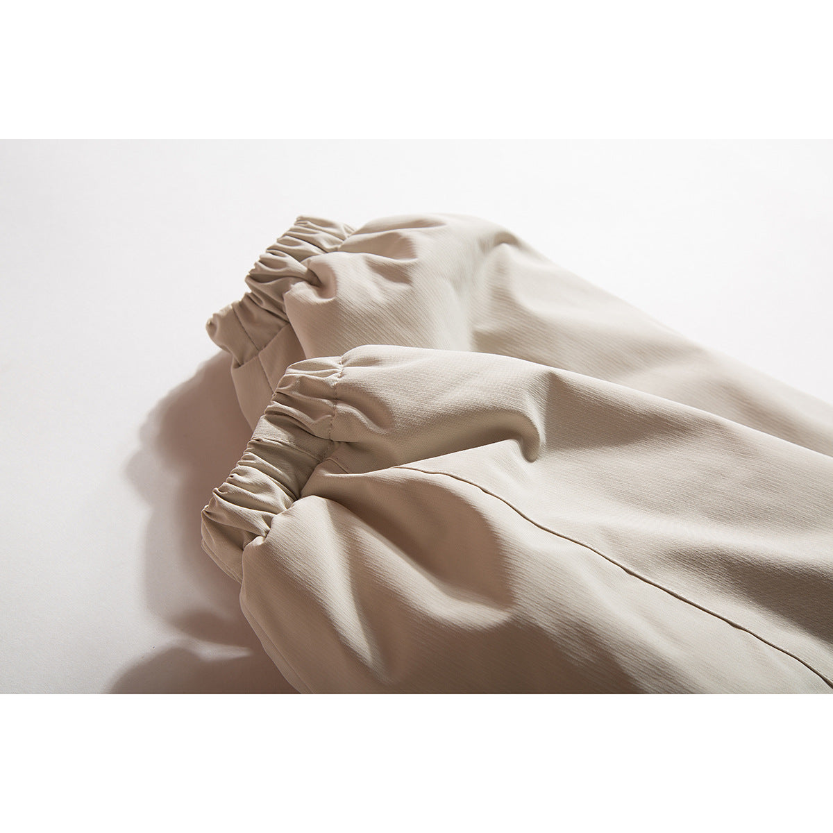 Close-up of gathered elastic cuffs and seams on a light beige jacket.
