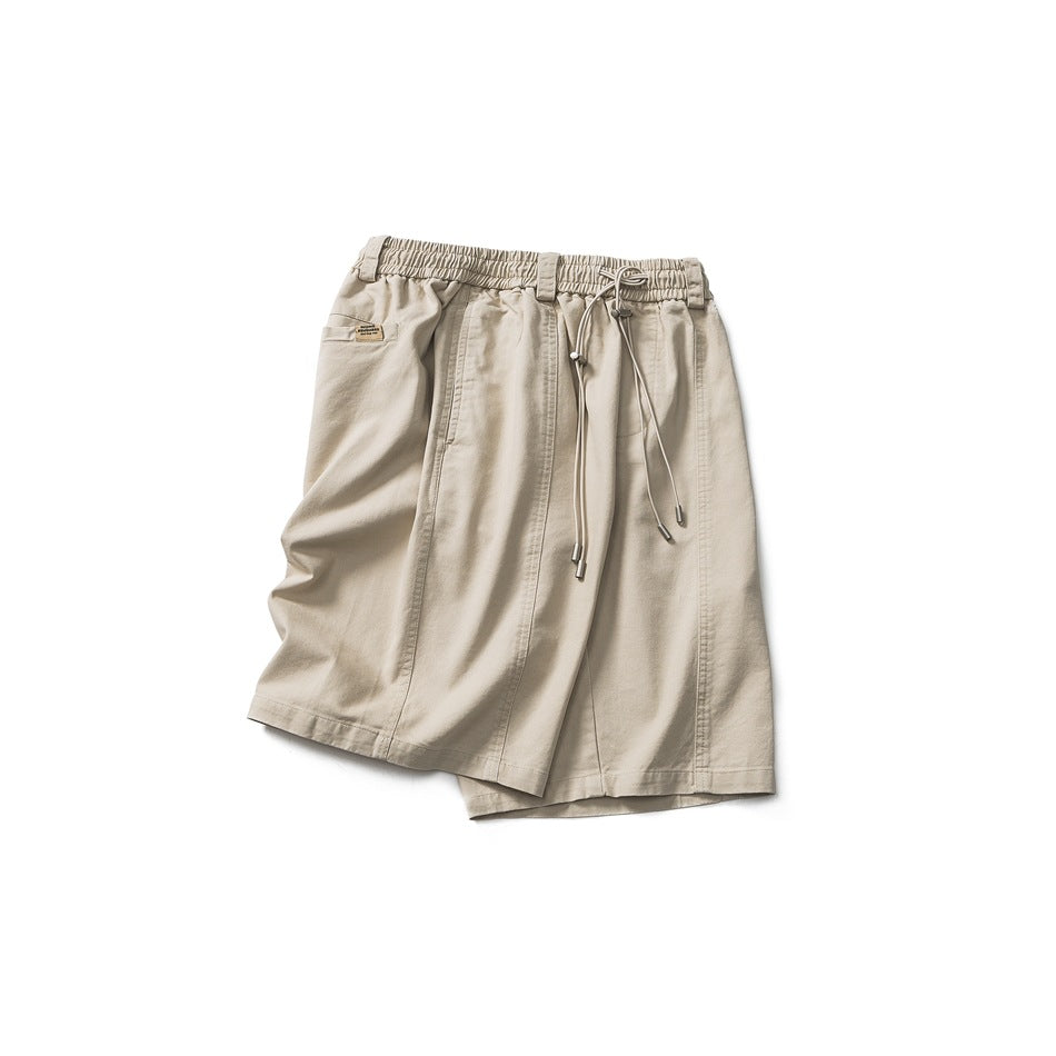 Front view of beige knee-length shorts with an elastic drawstring waist, side pockets, and stitched panels.