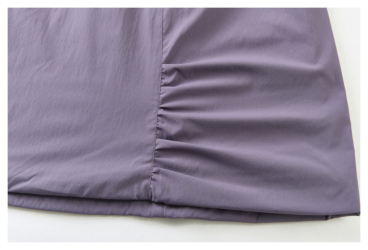 Close-up of the purple skirt hem showing a side seam and gathered fabric.