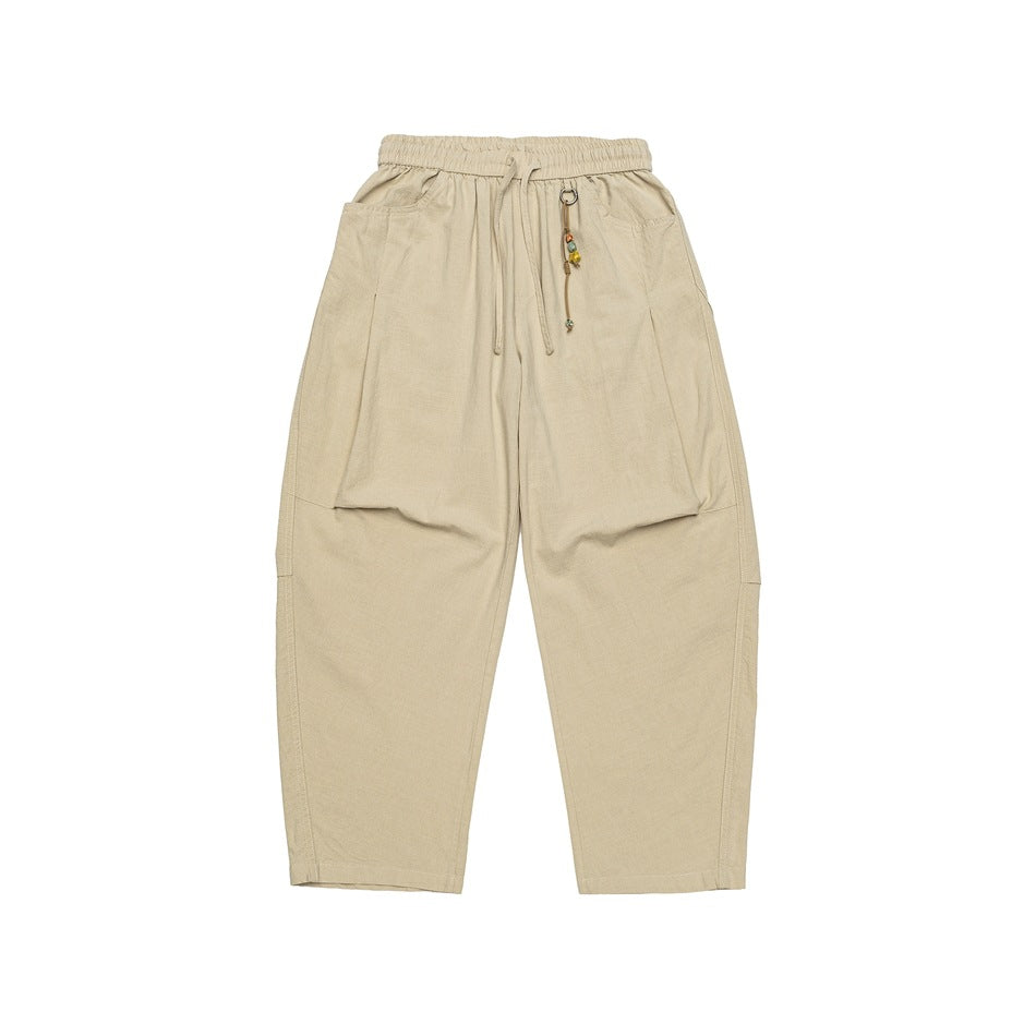 Light khaki wide-leg drawstring pants with large side pockets and a bead charm, flat lay front view