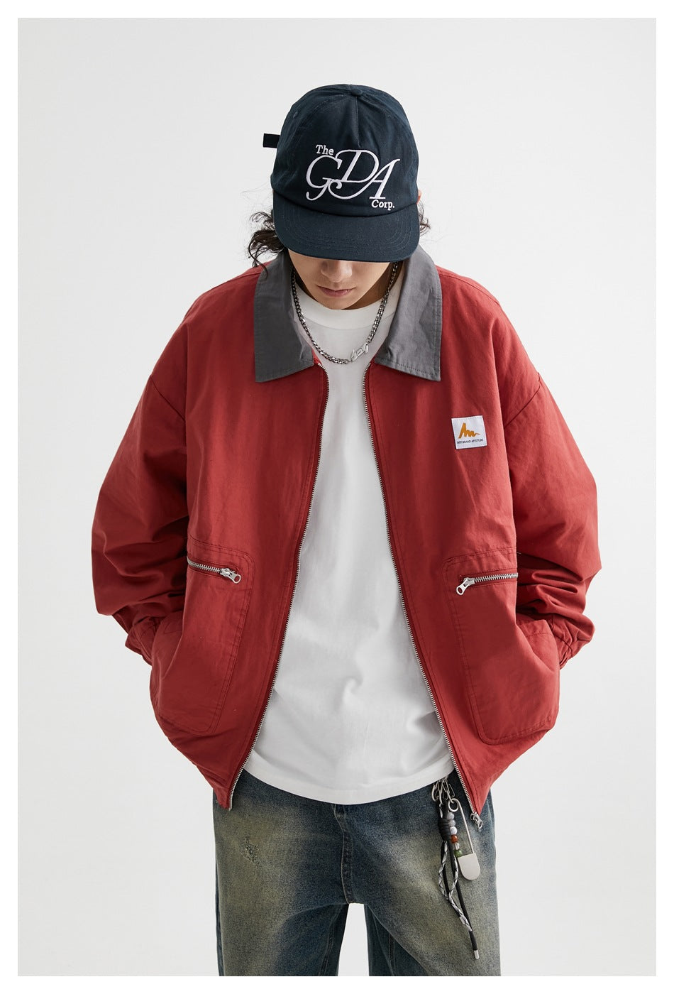 Front view of a model in a rust-red jacket with gray collar, zip front, and two large zippered pockets.