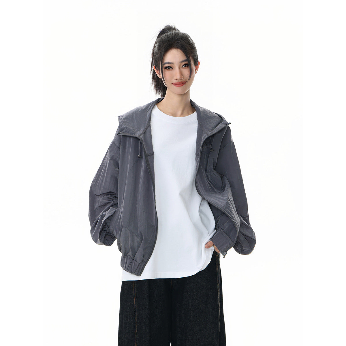 Model wearing an open charcoal-gray hooded jacket over a white shirt, shown from the front.