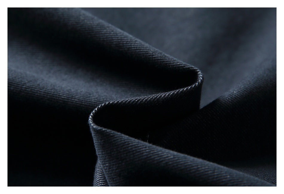 Macro view of dark denim fabric folded to show its texture and edge.