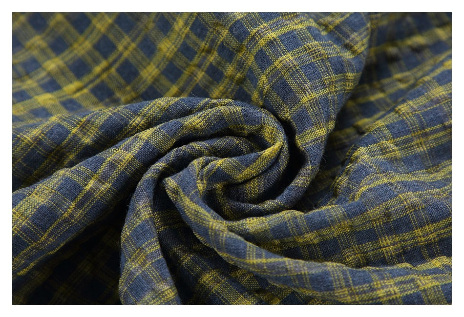 Close-up of gathered navy fabric with a mustard-yellow plaid pattern.