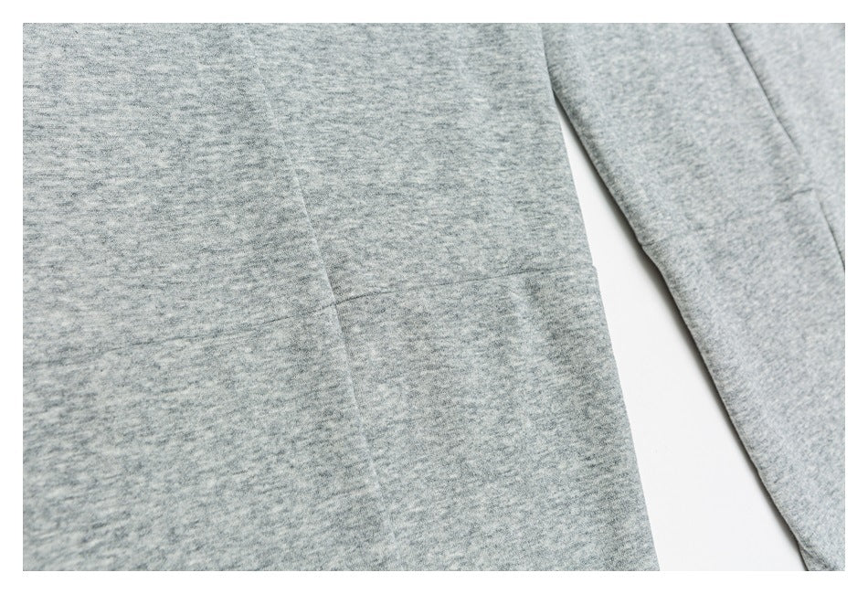 Close-up of gray heathered garment fabric with a stitched panel and a matching sleeve.