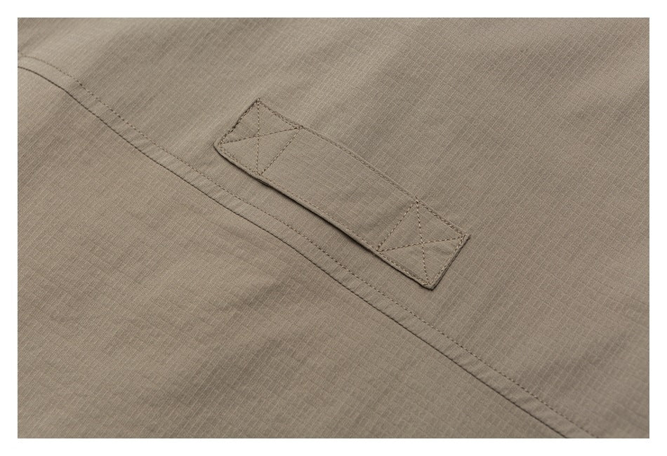 Close-up of a taupe fabric tab with cross-stitching beside a double-stitched seam.