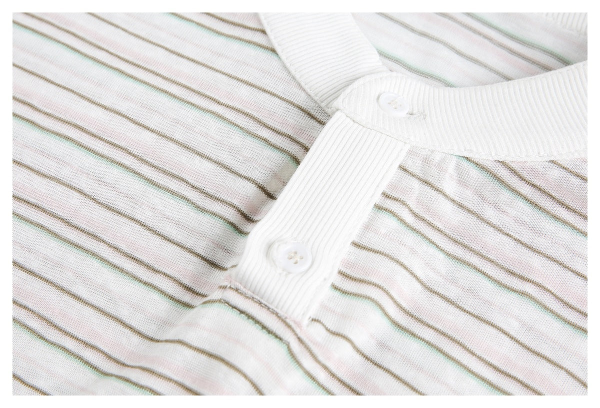 Close-up of two white buttons on the ribbed placket of a cream shirt with fine muted stripes.