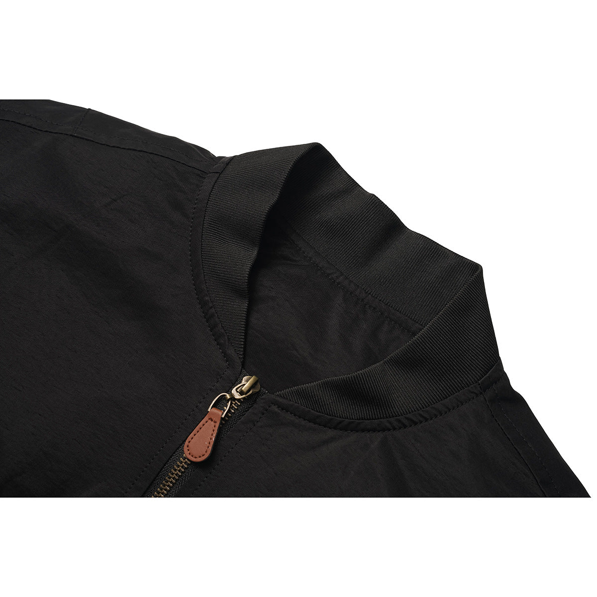 Close-up of a black jacket's ribbed collar and brass-tone zipper with a brown pull tab.