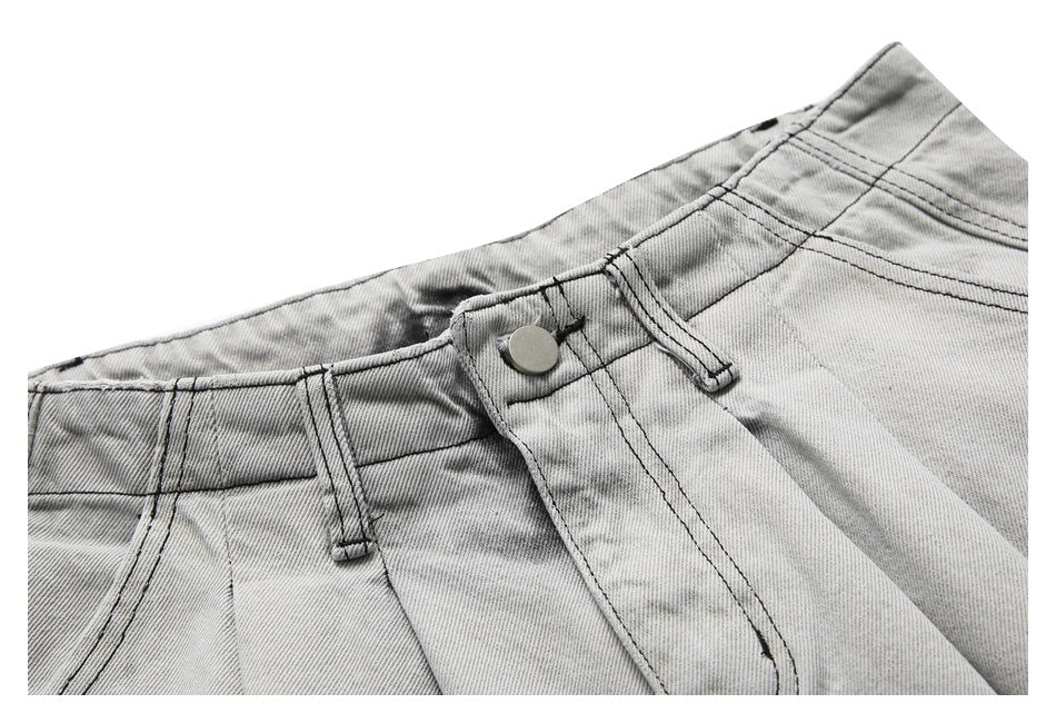 Close-up of the waistband, belt loops, button and fly on gray washed denim shorts.