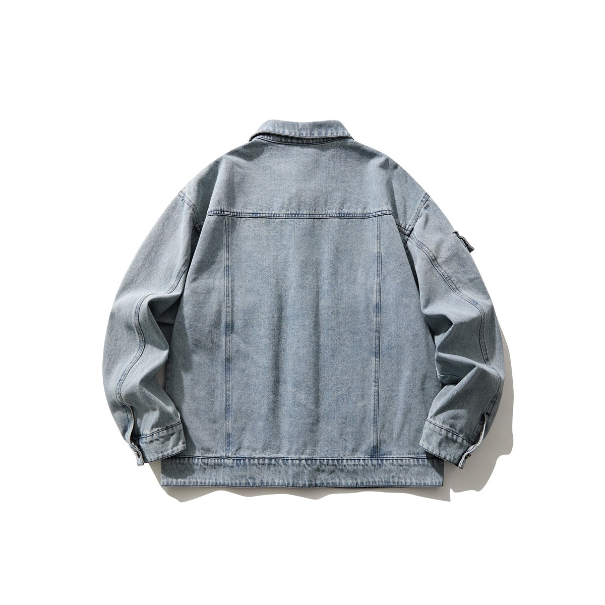 Back view of a light blue washed denim jacket with a plain panel, long sleeves, and a small sleeve pocket.
