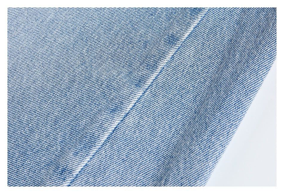 Close-up of blue denim with a diagonal seam and fine twill texture.