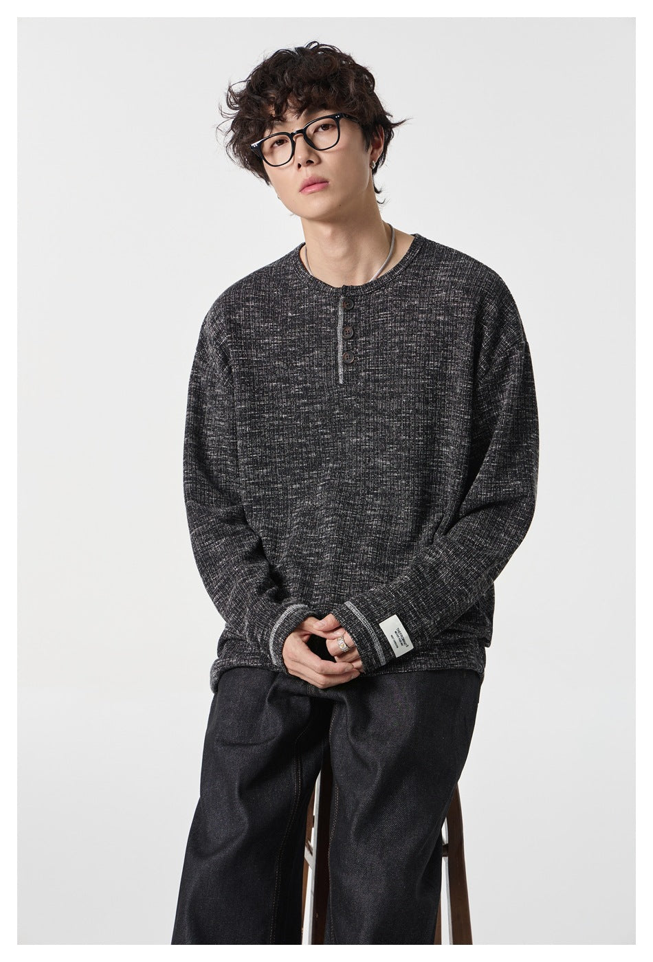 Close view of a model wearing a charcoal heathered long-sleeve henley with a three-button placket.