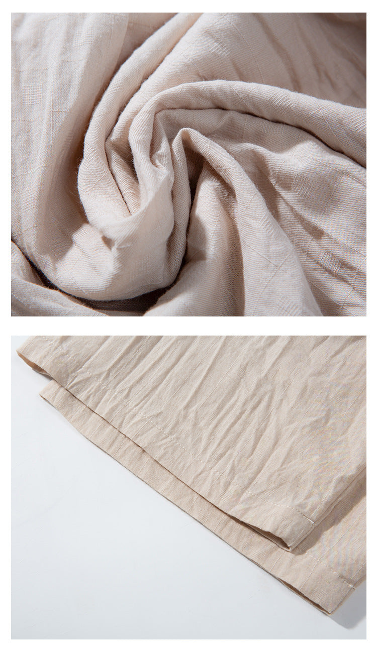 Close-up of light beige garment fabric and its neatly stitched hem, shown laid flat.