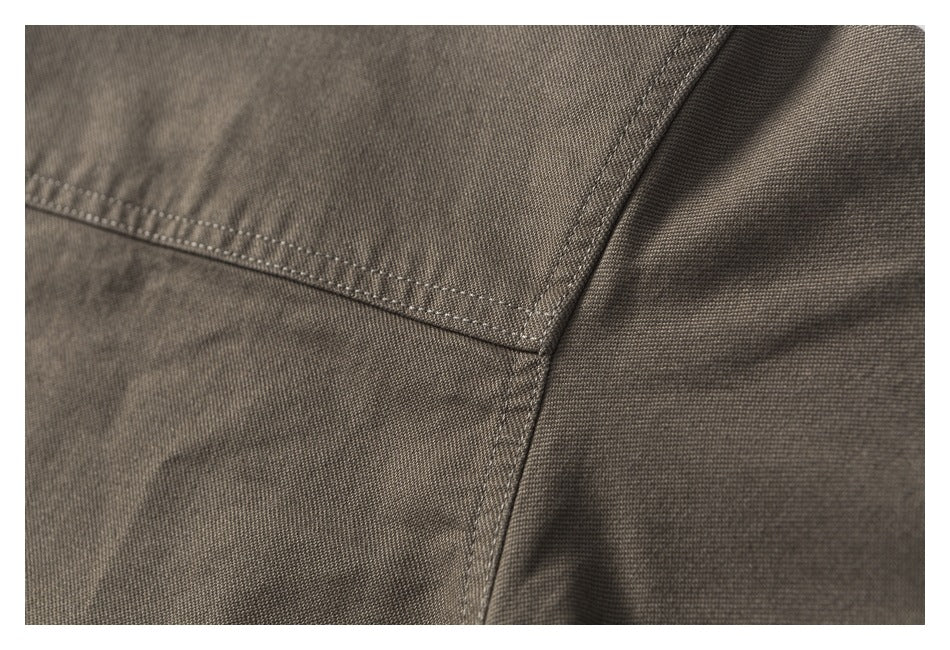 Close-up showing stitching and a curved seam on brown-gray garment fabric.