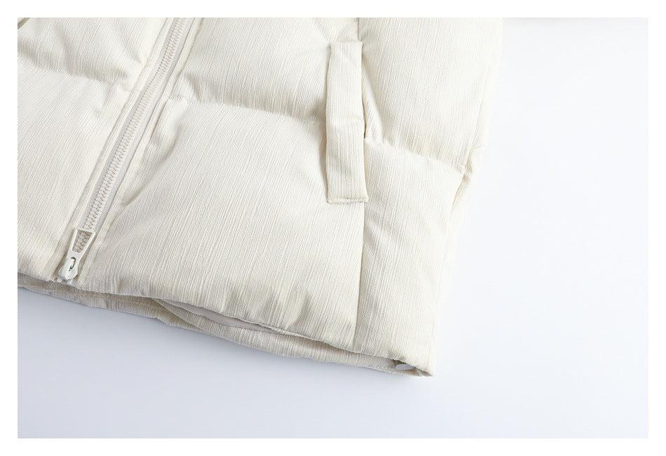 Close-up of the ivory jacket's front pocket opening, zipper, and lower hem.